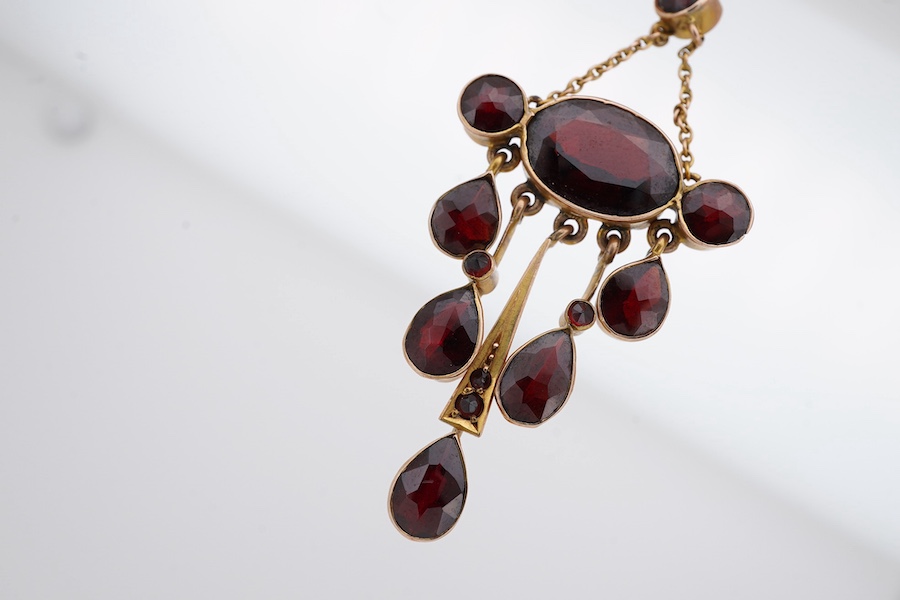 An early 20th century yellow metal and garnet cluster set drop pendant, 46mm, together with a similar opal set drop pendant, stamped '9', 37mm, gross weight 4.5 grams. Condition - fair to good